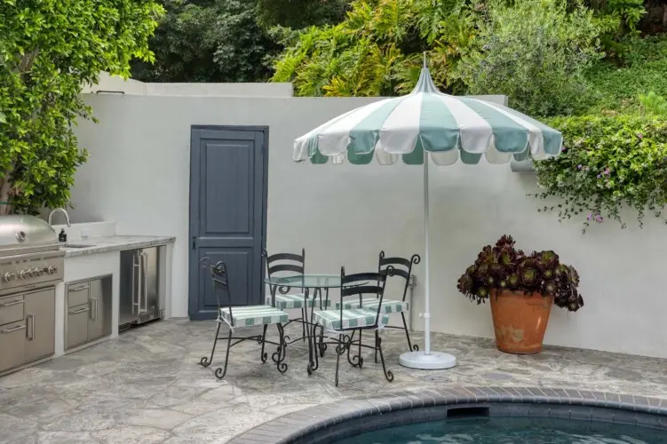 Outdoor seating area with table, chairs, and umbrella next to a pool at Laurel Canyon Classic Hollywood Residence W/ Pool by Open Air Homes.