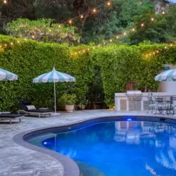 Outdoor pool area with seating, umbrellas, and barbecue setup at Laurel Canyon Classic Hollywood Residence by Open Air Homes.