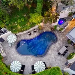 Aerial view of the outdoor pool area with seating, umbrellas, and greenery at Laurel Canyon Classic Hollywood Residence by Open Air Homes.