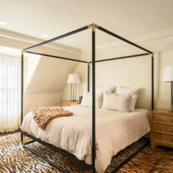 Bedroom interior of Laurel Canyon Classic Hollywood Residence W/ Pool featuring a bed with a canopy frame, bedside tables with lamps, and a large window with curtains by Open Air Homes.