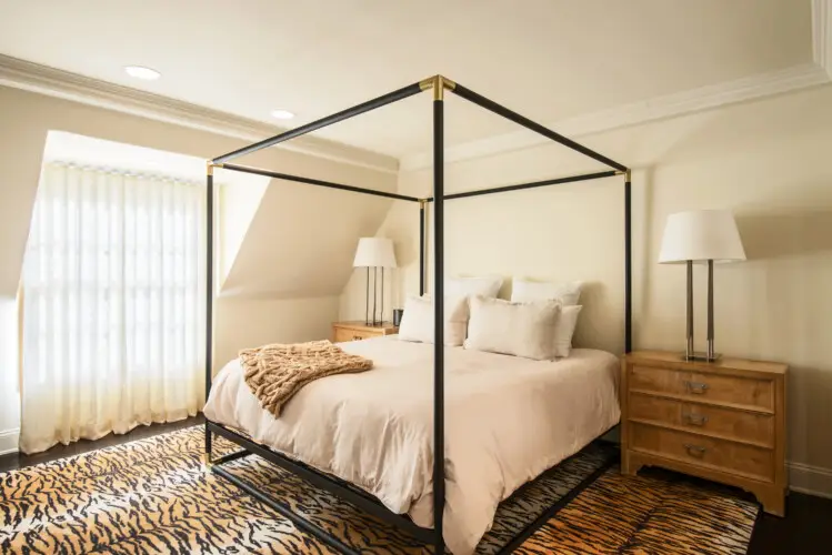 Bedroom interior of Laurel Canyon Classic Hollywood Residence W/ Pool featuring a bed with a canopy frame, bedside tables with lamps, and a large window with curtains by Open Air Homes.