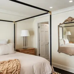 Bedroom interior of Laurel Canyon Classic Hollywood Residence W/ Pool featuring a bed with a canopy frame, bedside table with a lamp, and a large decorative mirror by Open Air Homes.