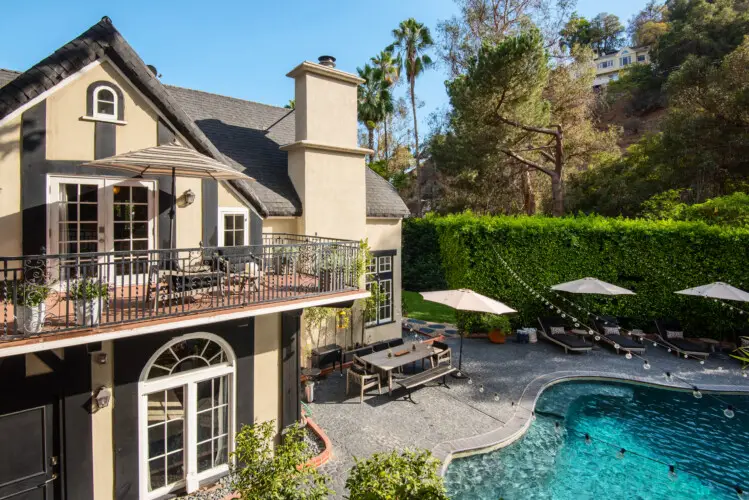 Exterior view of Laurel Canyon Classic Hollywood Residence W/ Pool with balcony, outdoor seating, and swimming pool surrounded by greenery by Open Air Homes.