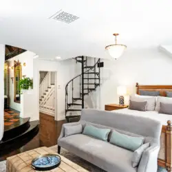 Bedroom interior of Laurel Canyon Classic Hollywood Residence W/ Pool with exposed wooden beams, bed, spiral staircase, and balcony by Open Air Homes.