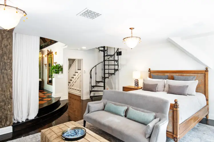 Bedroom interior of Laurel Canyon Classic Hollywood Residence W/ Pool with exposed wooden beams, bed, spiral staircase, and balcony by Open Air Homes.