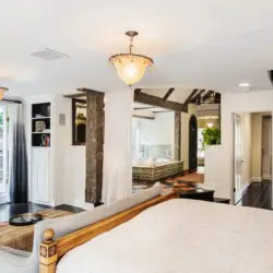 Bedroom interior of Laurel Canyon Classic Hollywood Residence W/ Pool with exposed wooden beams, bed, spiral staircase, and balcony by Open Air Homes.