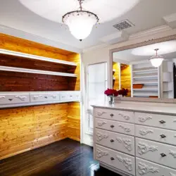 Closet interior of Laurel Canyon Classic Hollywood Residence W/ Pool with wooden shelves, drawers, dresser, and chandelier by Open Air Homes.