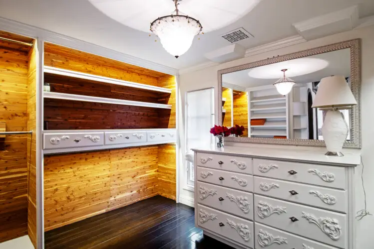 Closet interior of Laurel Canyon Classic Hollywood Residence W/ Pool with wooden shelves, drawers, dresser, and chandelier by Open Air Homes.