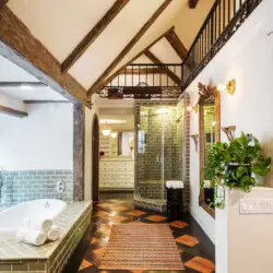 Bathroom interior of Laurel Canyon Classic Hollywood Residence W/ Pool with exposed wooden beams, bathtub, shower, and vanity by Open Air Homes.