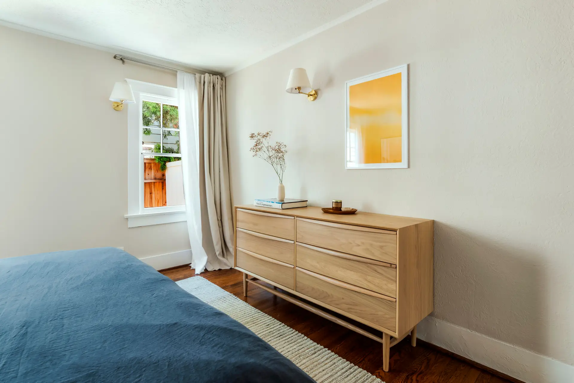 Redondo Beach Monthly Airbnb Management - Bedroom with a large bed, wooden dresser, and window in a luxury vacation rental managed by Open Air Homes.
