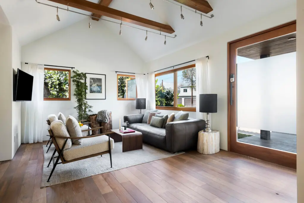 Modern living room with stylish furniture, artwork, and large television - Open Air Homes