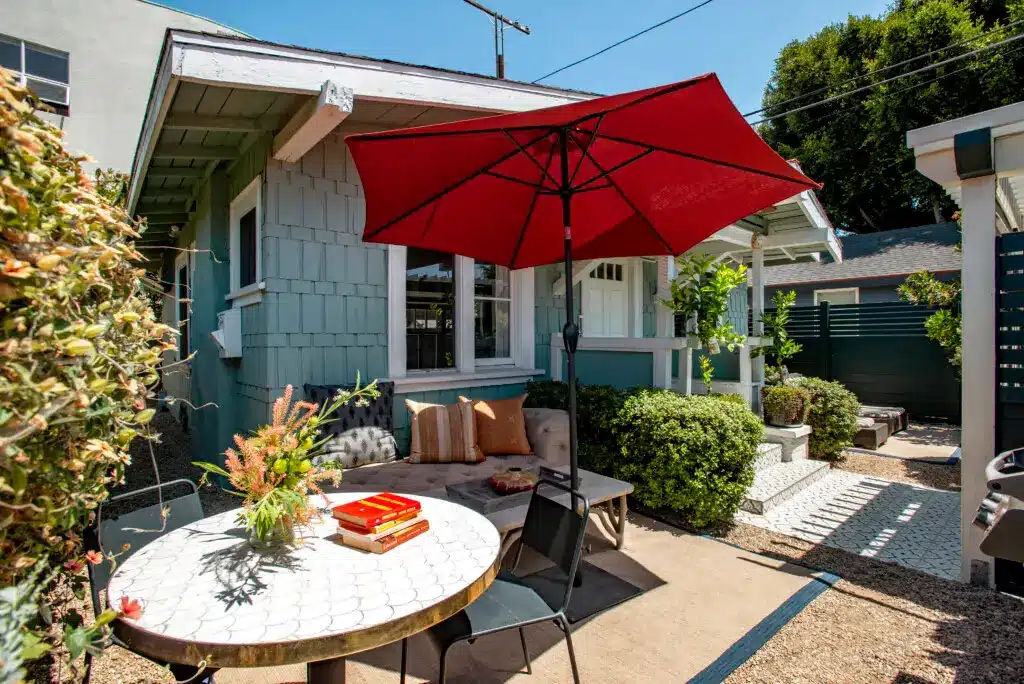 Why Hiring an Experienced Airbnb Manager in Venice Beach Matters 1 Santa Monica Monthly Airbnb Management - Outdoor seating area with a table, chairs, and a red umbrella at Venice Beach Bungalow.