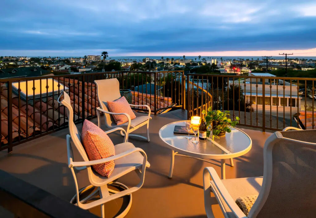 Top 5 Reasons to Book This Redondo Beach Monthly Rental with Ocean Views 1 Rooftop deck with outdoor seating, table, and city view at dusk at Redondo Beach monthly rental.