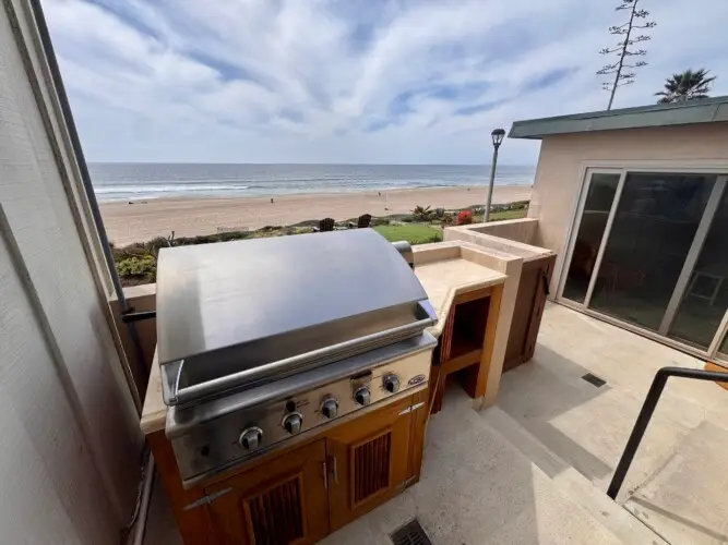Outdoor barbecue area with beachfront view at The Triton Manhattan Beachfront Escape rental by Open Air Homes.