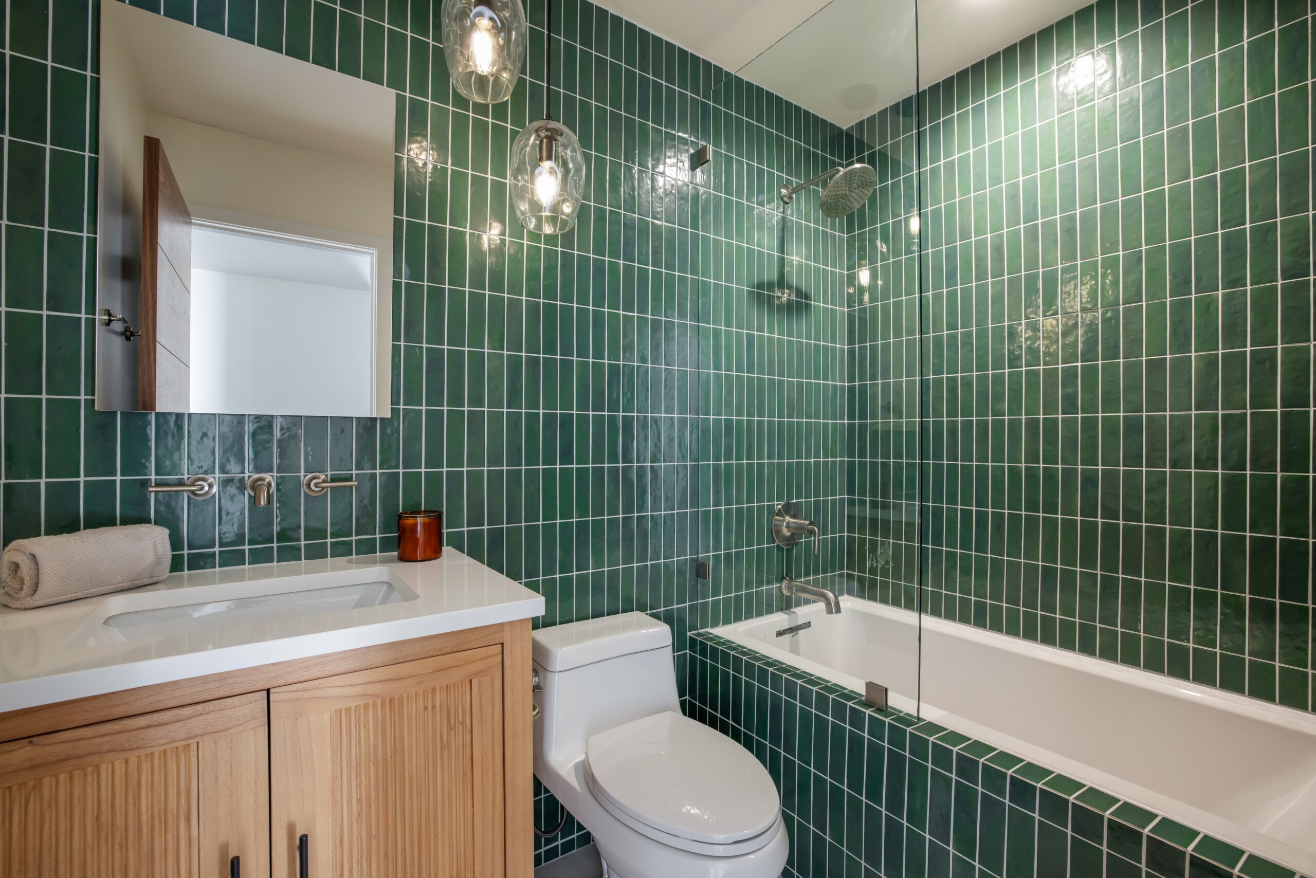 Bathroom with green tiles, bathtub, and wooden vanity in Pacific Ave short-term rental, Venice Beach, Open Air Homes
