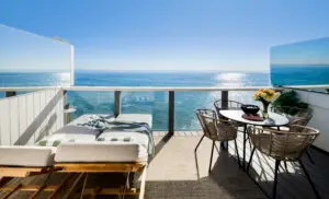 Outdoor deck with sun loungers and dining table overlooking the ocean – Open Air Homes
