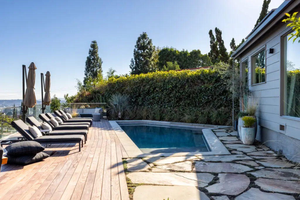 Eagle Rock Airbnb Management - Pool area with lounge chairs and greenery at Hollywood Hills Home - Open Air Homes