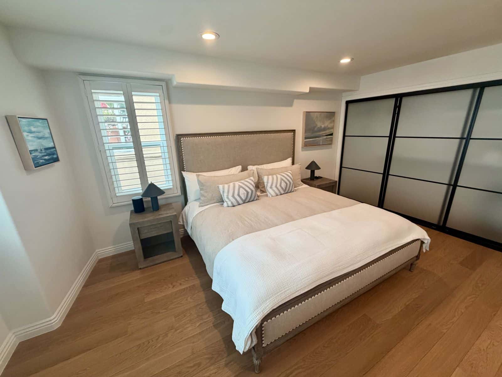 Primary bedroom with two coastal paintings and mirrored closet doors