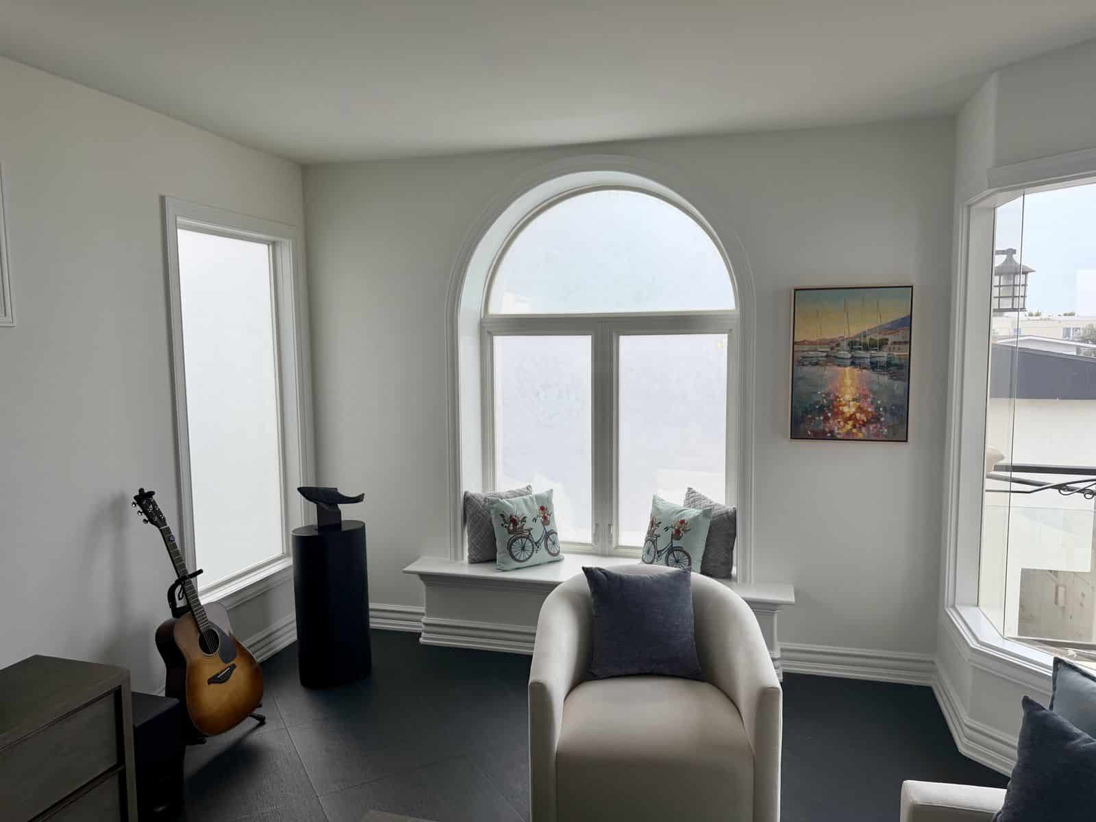 Sitting area with an arched window seat and a harbor at sunset painting