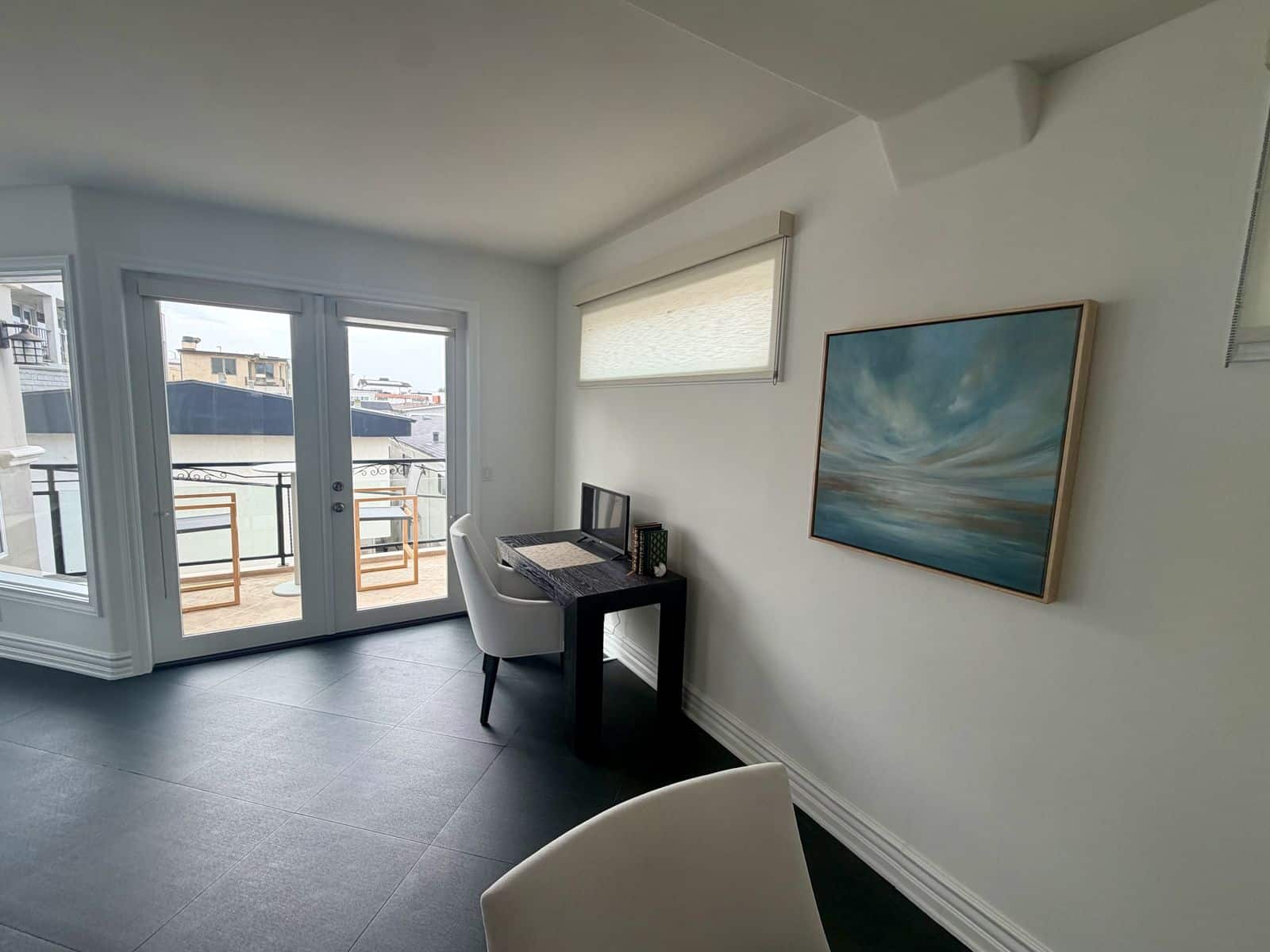 Dedicated workspace beside balcony doors under a large cloud and sea painting