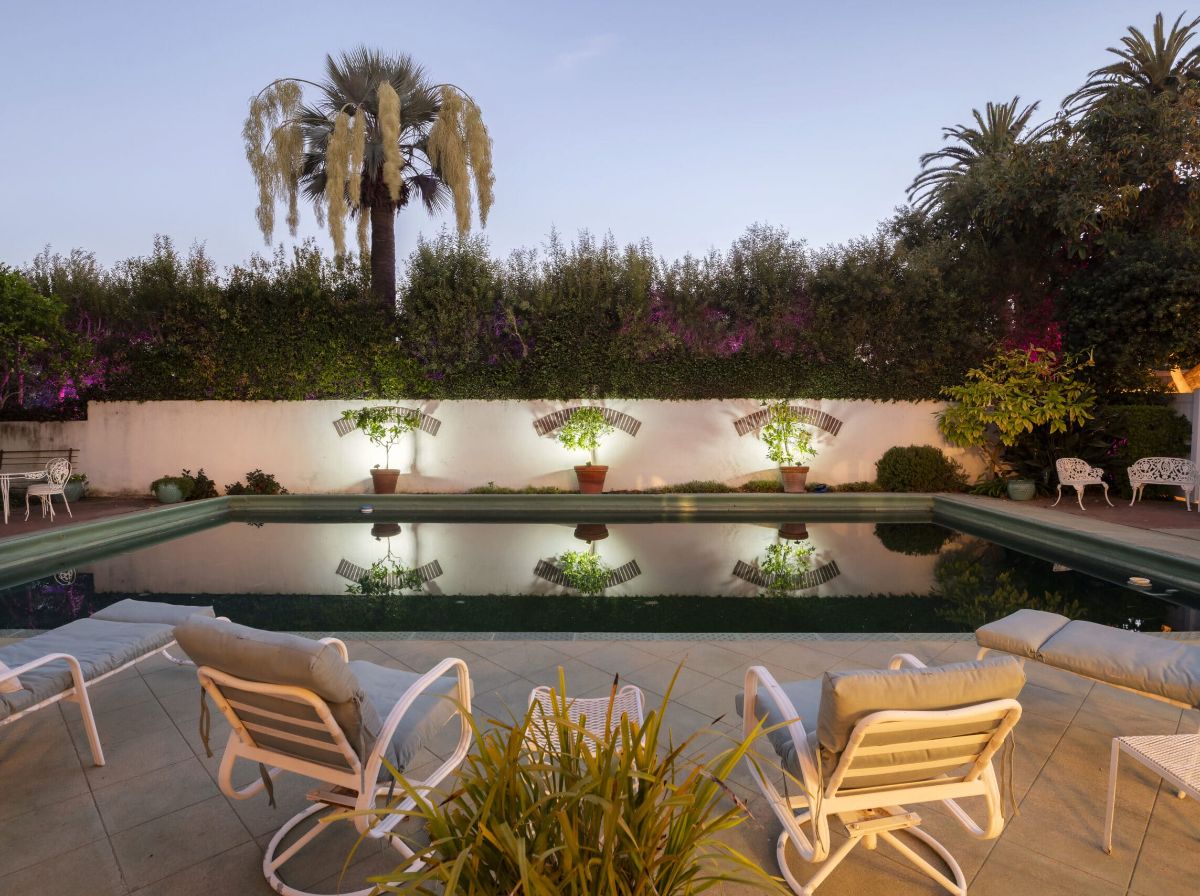 Pool at dusk with uplit garden walls at a Pacific Palisades estate managed by Open Air Homes in Los Angeles