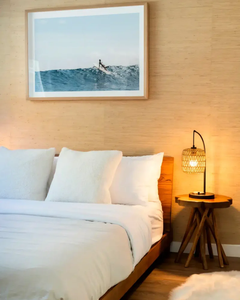 Modern bedroom with a comfortable bed, bedside table, and surfer artwork – Open Air Homes