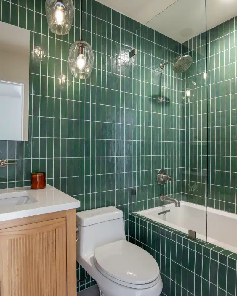 Bathroom with green tiles, bathtub, and wooden vanity in Pacific Ave short-term rental, Venice Beach, Open Air Homes