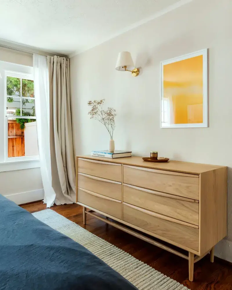 Redondo Beach Monthly Airbnb Management - Bedroom with a large bed, wooden dresser, and window in a luxury vacation rental managed by Open Air Homes.
