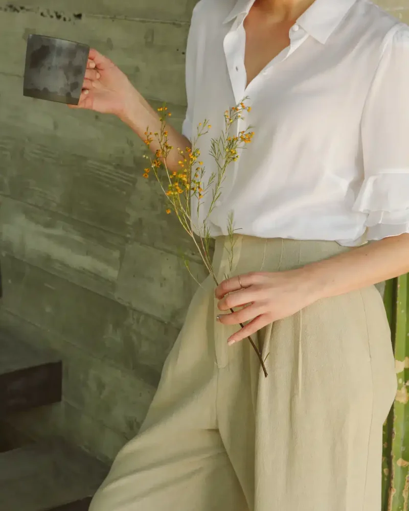 Person holding a mug and greenery, showcasing a relaxed lifestyle at Open Air Homes' luxury vacation rental.