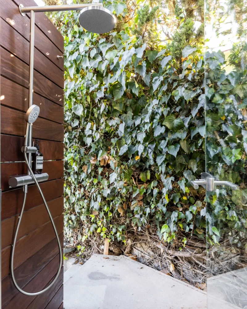 Eagle Rock Airbnb Management - Outdoor shower with wooden backdrop and greenery at Pacific Ave short-term rental, Venice Beach