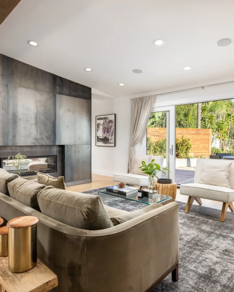Eagle Rock Airbnb Management - Living room with large sofa, coffee table, and large windows overlooking outdoor area at Hollywood Hills Home - Open Air Homes.