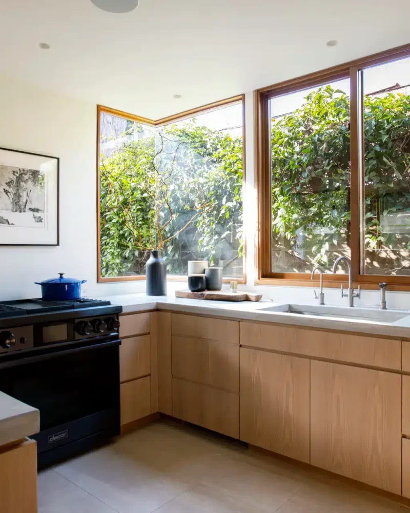 Westwood Airbnb Management - Modern kitchen with wooden cabinets, stove, and large windows overlooking greenery - Open Air Homes