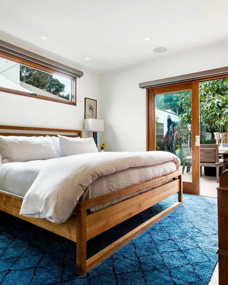 Open Air HomModern bedroom with wooden bed frame, bedside tables, and sliding glass door - Open Air Homeses helps homeowners navigate LA's short-term rental laws.